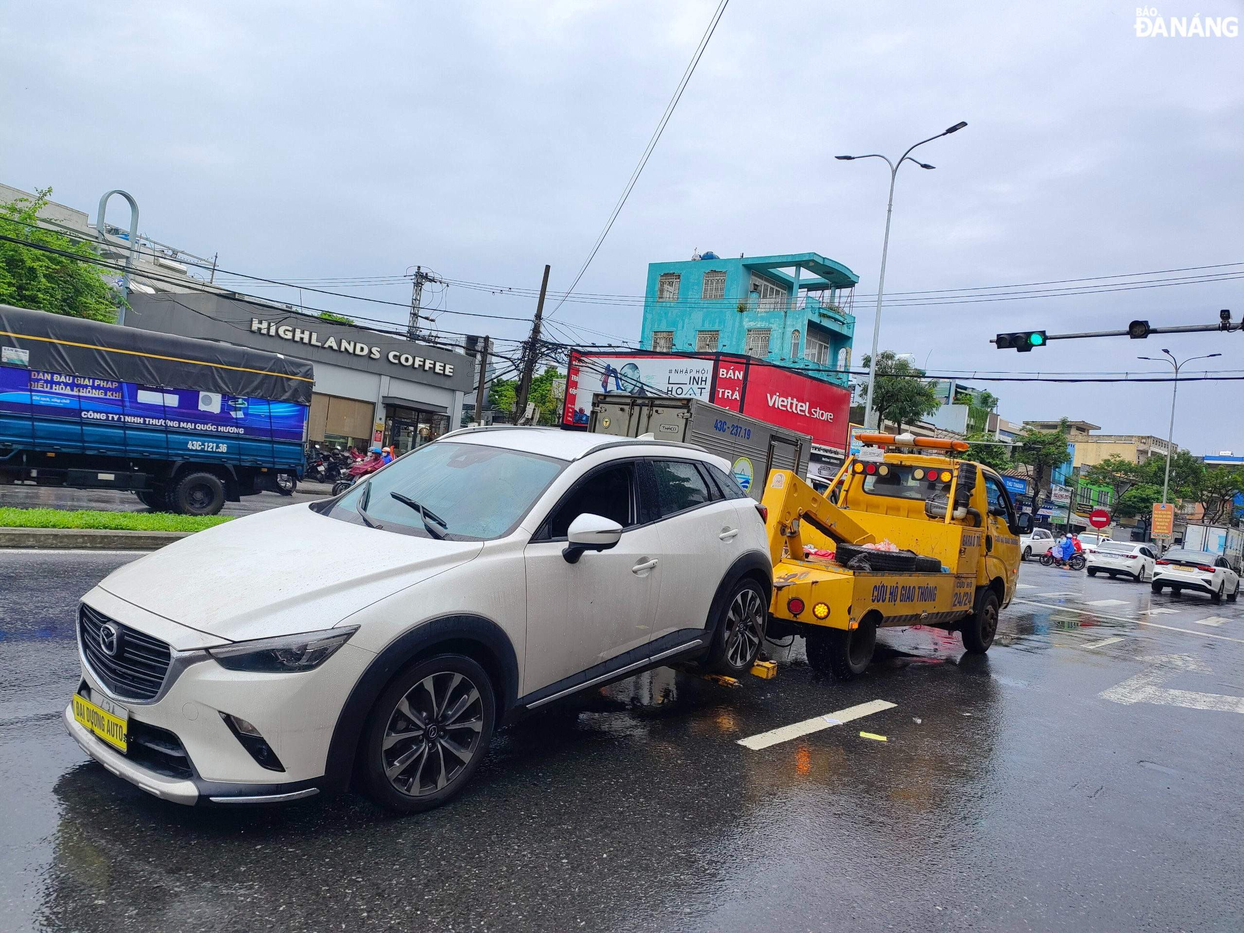 A broken down car was towed by a crane truck to the garage for repair.