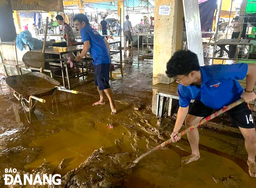 Youth Union members and young people in Hoa Khanh Bac Ward, Lien Chieu District, taking part in flood cleanup work at the Thanh Vinh Traditional Market. Photo: H.T