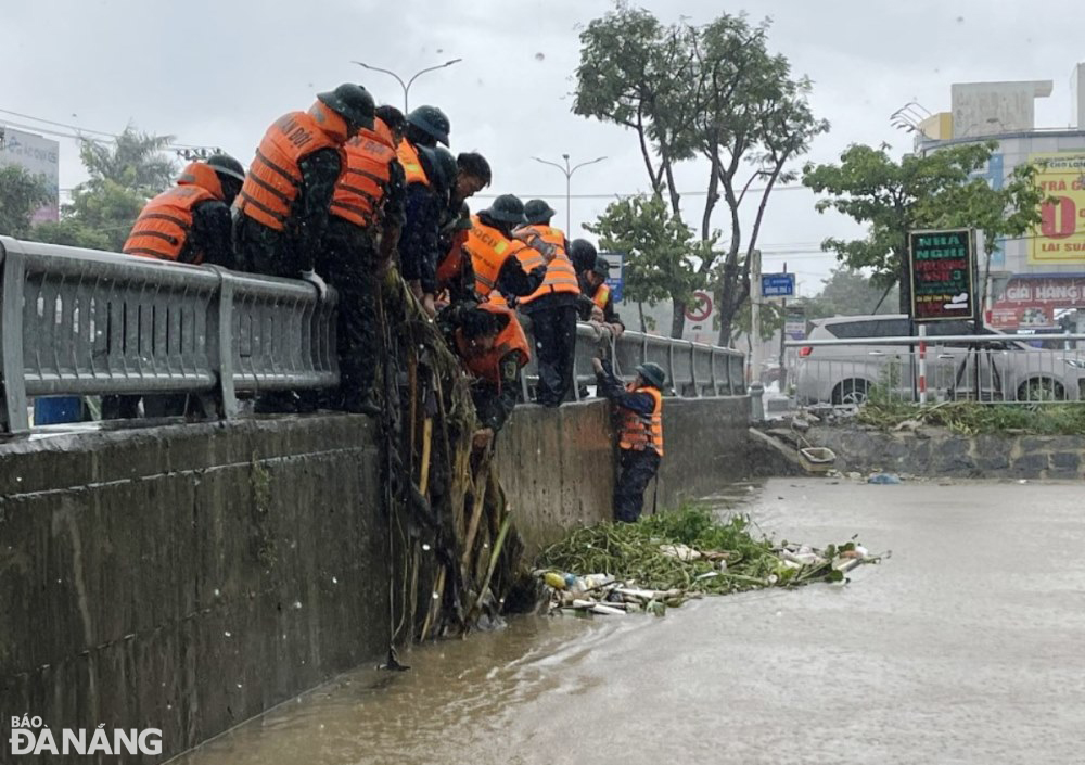 Lực lượng quân đội vớt bèo, rác mắc kẹt tại cầu qua kênh Đa Cô để khơi thông thoát nước, chống ngập úng tại khu vực đường Mẹ Suốt, Hoàng Văn Thái.