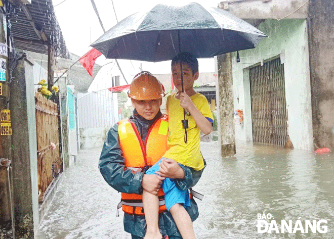 Lực lượng Dân quân thường trực phường Thanh Khê Tây (quận Thanh Khê) hỗ trợ người dân khu vực Khe Cạn bị ngập lụt đến nơi trú tránh an toàn. Ảnh: D.Q