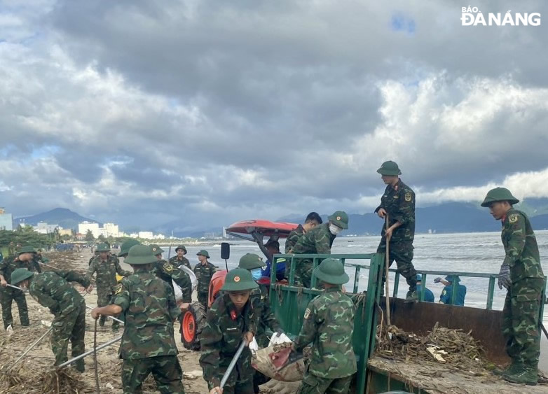 Người cho rác vào bao, người khiêng rác đổ lên xe, vận chuyển đi xử lý. Ảnh: LÊ HÙNG 