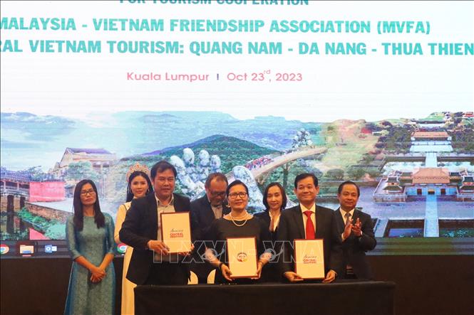 Representatives of the Tourism Promotion Centre of Quang Nam -  Da Nang - Thua Thien - Hue and Chairman of the Malaysia - Vietnam Friendship Association (middle) sign a memorandum of understanding on communication cooperation and tourism promotion. Photo: VNA