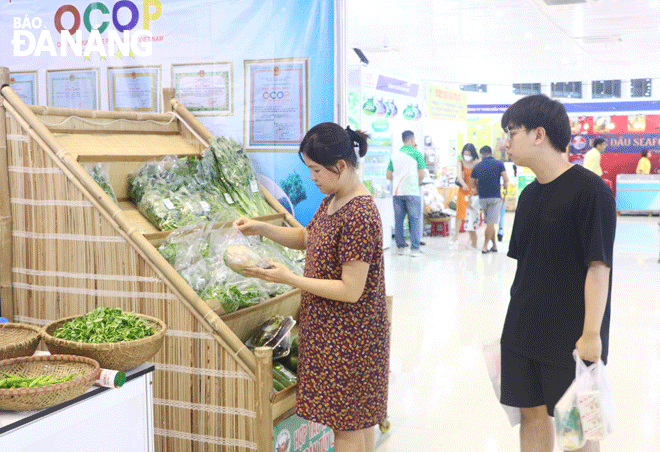 People shop for vegetable, tuber, and fruit products developed by the Tuy Loan Safe Vegetable Production and Consumption Service Cooperative at the Da Nang Vietnamese Goods Fair 2023 - Honouring OCOP products. Photo: VAN HOANG