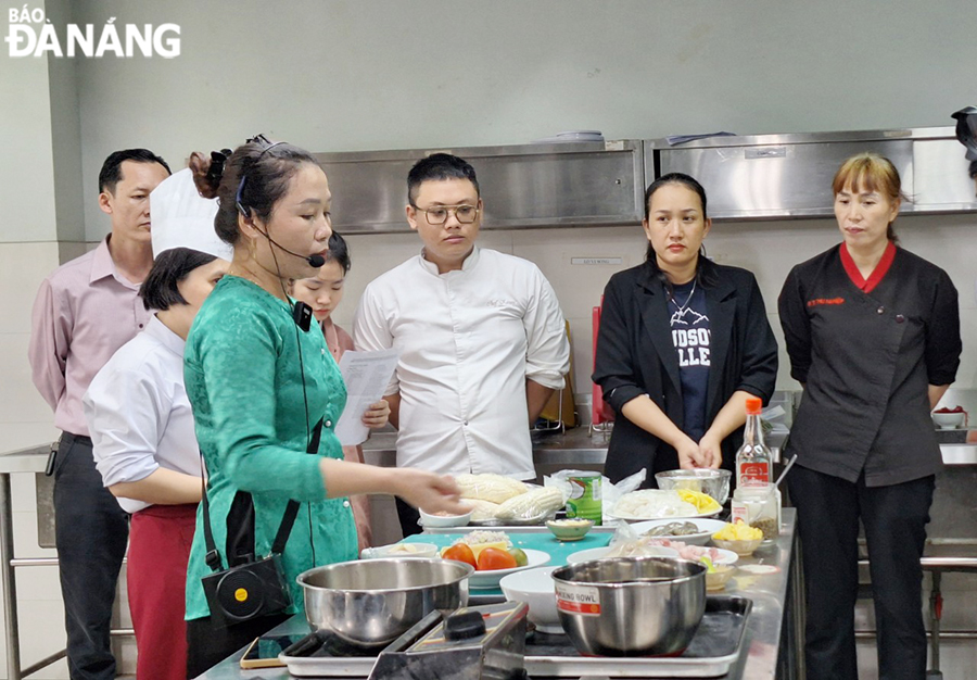 Artisan Tran Thi Dong (in ‘Ao Dai’) instructs chefs to prepare Phu Chiem-style Quang noodles. Photo: THU HA