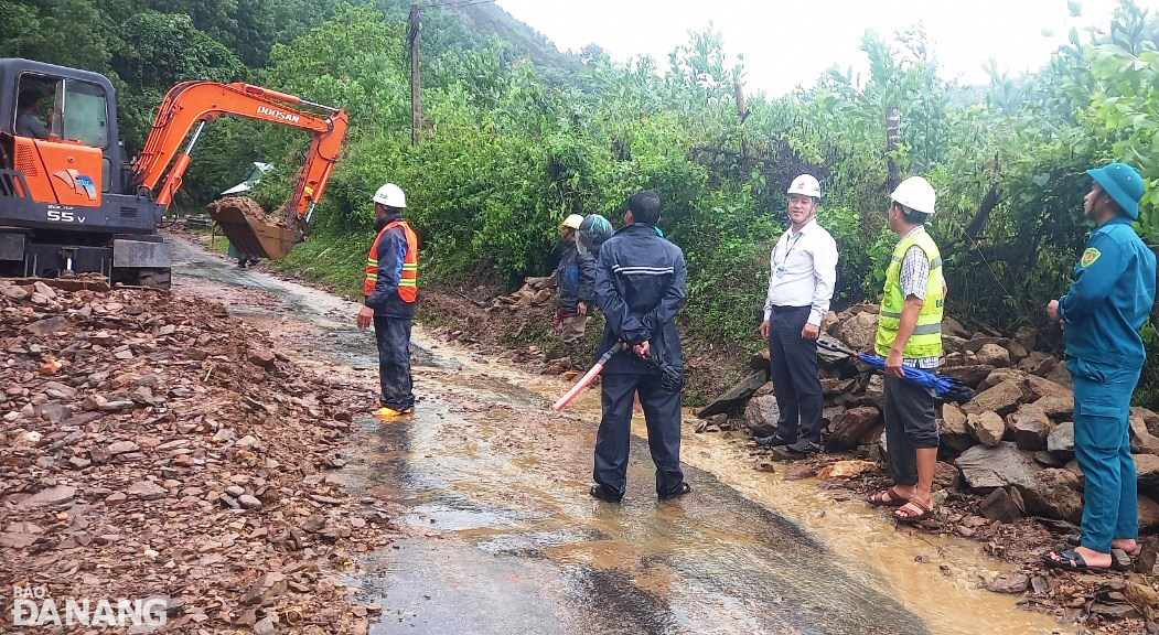 Lãnh đạo UBND xã Hòa Phú (huyện Hòa Vang) phối hợp với đơn vị liên quan huy động phương tiện cơ giới xử lý các điểm sạt lở đất, đá dọc Quốc lộ 14G. Ảnh: H.H