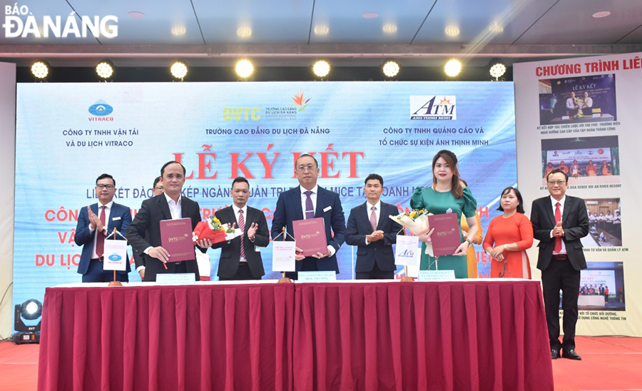 Headmaster of the Da Nang Vocational Tourism College (middle, front row) signs a training cooperation agreement with tourism businesses. Photo: THU HA