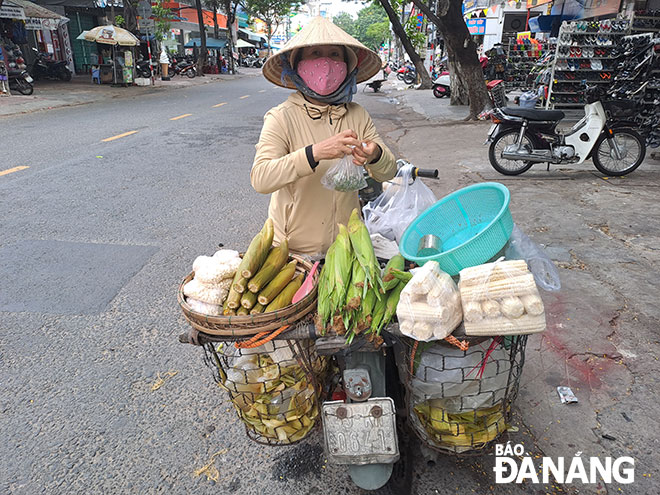 Ở tuổi 53, bà Nguyễn Thị Mai (ở Hội An) đã có ngót nghét gần 40 năm buôn bán hàng rong. Nhờ các con hướng dẫn, giờ bà sử dụng thành thạo công nghệ để việc kinh doanh chủ động hơn. Ảnh: KHÁNH HÒA	