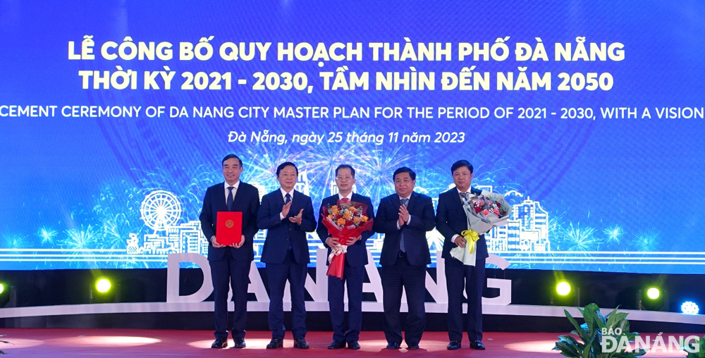 Deputy Prime Minister Tran Hong Ha (2nd, from left), Minister of Planning and Investment Nguyen Chi Dung (4th, from left) hand over the Prime Minister's decision on approving Da Nang Master Plan for the 2021 - 2030 period, with a vision toward 2050 for the Da Nang leaders. Photo: HOANG HIEP