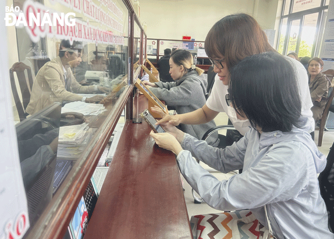 Công chức bộ phận “Một cửa” UBND quận Hải Châu hướng dẫn người dân sử dụng dịch vụ công trực tuyến. Ảnh: M.Q