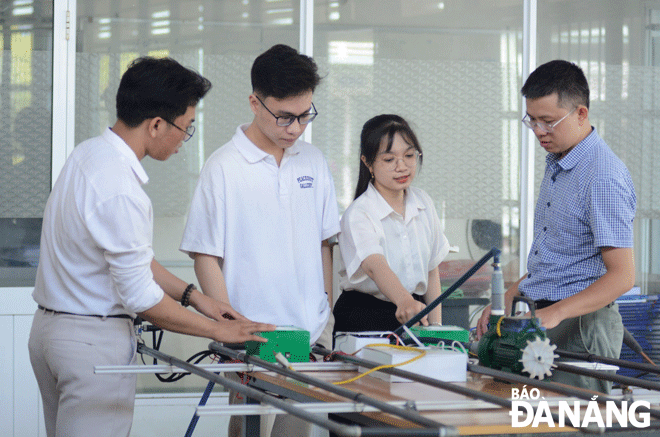 Tiến sĩ Phạm Thanh Phong (bên phải) và các sinh viên nghiên cứu mô hình thiết kế “Thiết bị chẩn đoán và giám sát vị trí điểm rò rỉ trong hệ thống đường ống dẫn chất lỏng”. Ảnh: V.D	