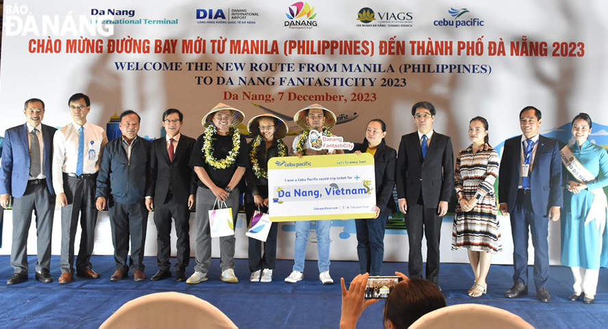 Vice Chairman of the Da Nang People's Committee Tran Chi Cuong (4th, right) presents souvenirs and vouchers for round-trip flight tickets from Manila to Da Nang of Cebu Pacific Air to three lucky passengers. Photo: THU HA