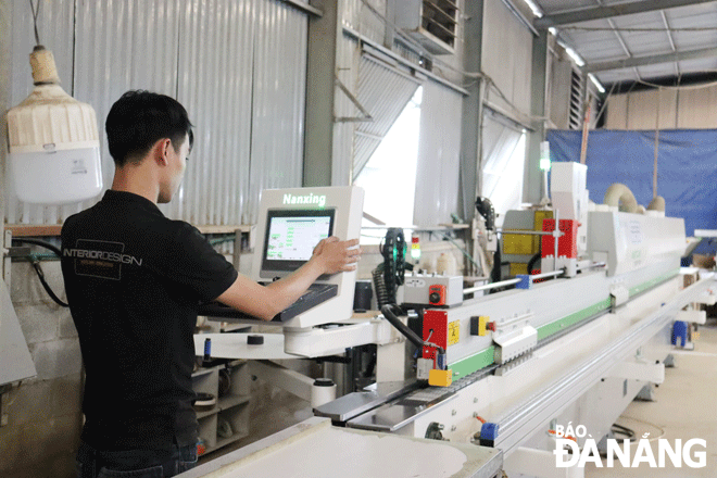 A worker operates an automatic edge banding machine at the P.A.D Art Design JSC. Photo: TRAN TRUC