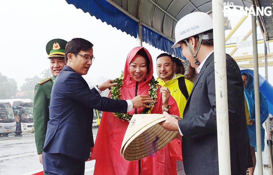 Deputy Director of the municipal Department of Tourism Tan Van Vuong (first left) giving flowers and gifts to the first cruise ship guests on New Year's Day. Photo: THU HA