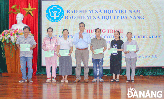 The Da Nang Social Insurance Department Vice Director Nguyen Hung Anh (middle) handling Social Insurance books to the disadvantaged in Hoa Cuong Bac Ward. Photo: NGUYEN QUANG