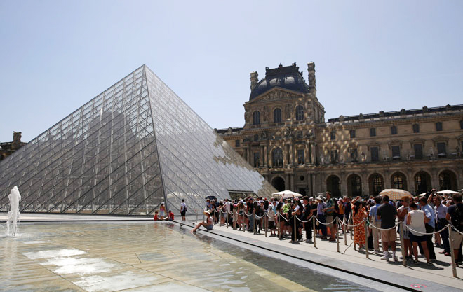 Du khách xếp hàng chờ ở lối vào Bảo tàng Louvre ở Paris hồi tháng 6-2022. Ảnh: AFP 