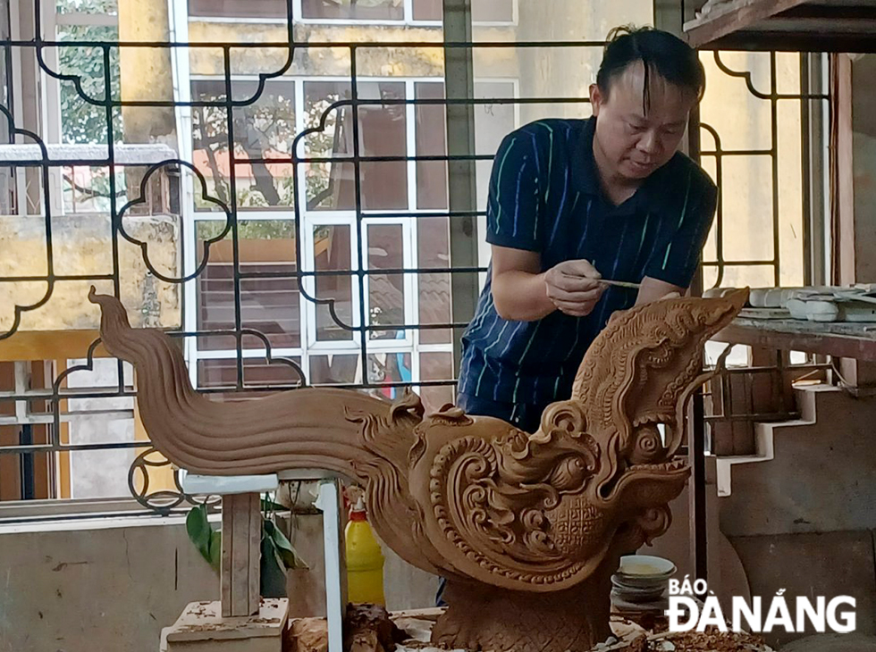 Artist Bui Van Kien, along with artists from the Bat Trang Pottery Village in Ha Noi, is busy making a stylized dragon mascot model themed 