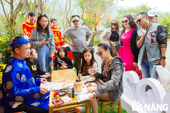 Tourist attractions will launch more activities to serve tourists during the Lunar New Year 2024. Tourists enjoy the calligraphy activity on the first day of the Lunar New Year at the Nui Than Tai Hot Spring Park. Photo: T.H