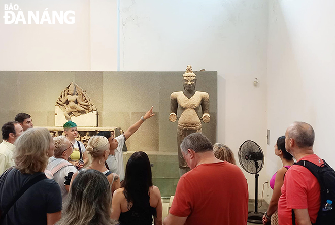 Foreigners listening to a museum guide describing the Shiva My Son C1 statue at the Da Nang Museum of Cham Sculpture