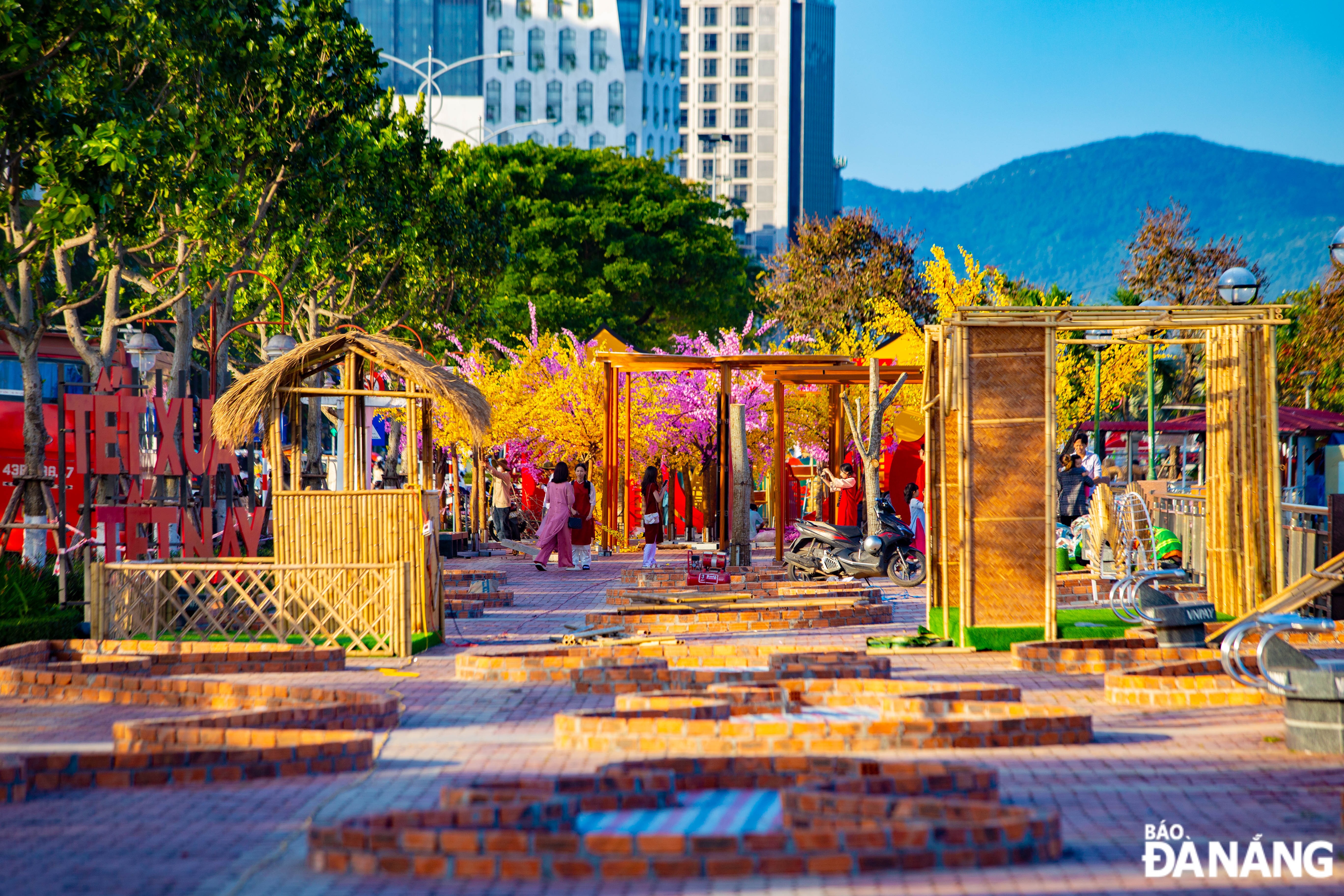 Floral decorations are underway along sidewalk of Bach Dang Street, opposite the APEC Sculpture Park.