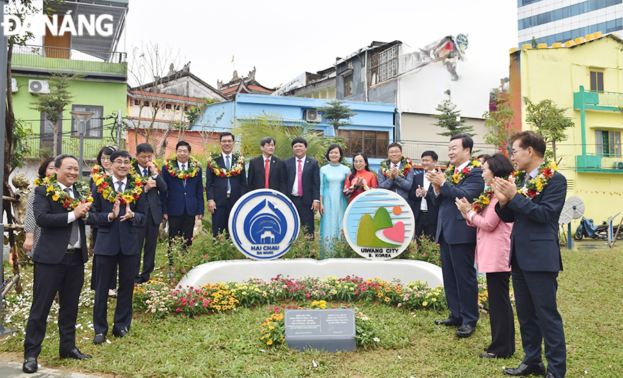 Đại diện lãnh đạo quận Hải Châu (bên trái) và đại diện lãnh đạo thành phố Uiwang, Hàn Quốc (bên phải) cùng gỡ băng khánh thành biểu tượng (logo) của hai thành phố. Ảnh: THU HÀ