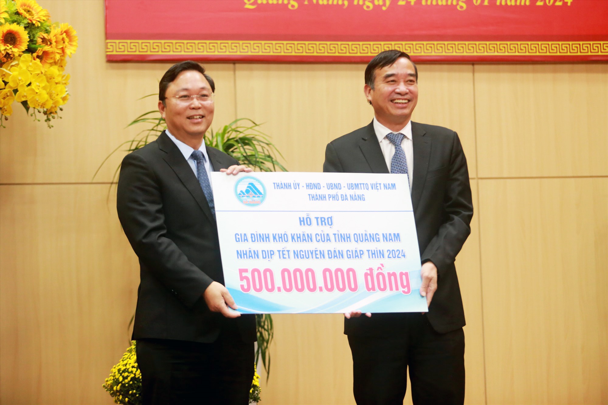 Chairman of the Da Nang People's Committee Le Trung Chinh (R) giving the city's donation of VND500 million to Quang Nam Province to carry out social security work