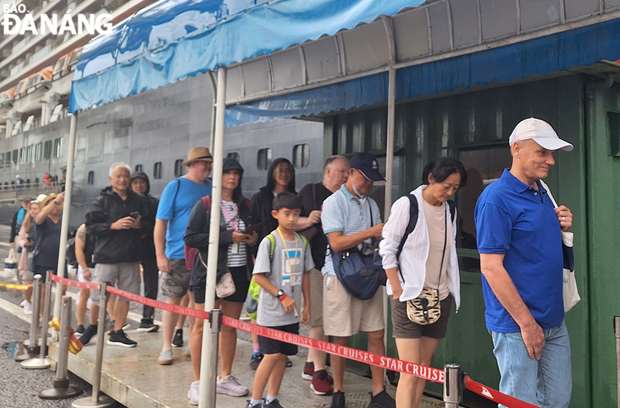 Tourists getting on shuttle buses to the city centre. Photo: NHAT HA