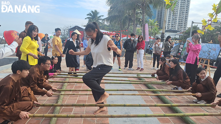 The game of ‘nhay sap’ (dance with bamboo poles) attracts much attention from people, especially international tourists. Photo: THU HA