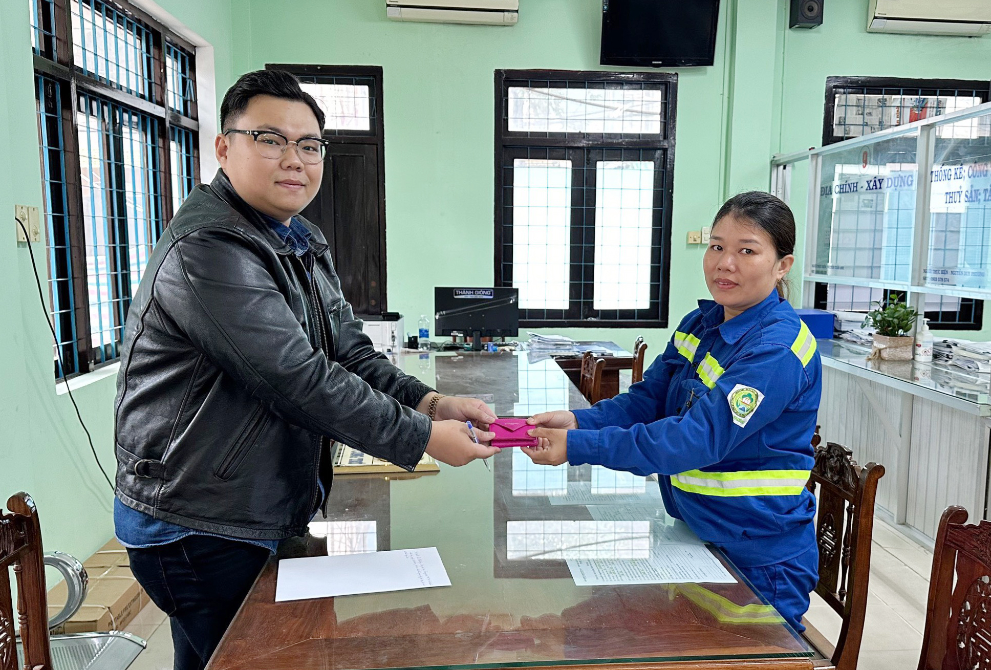 The Da Nang sanitation worker (right) gives the wallet to a representative of the Da Nang Visitor Centre to return it to the US owner. Photo courtesy of the Da Nang Visitor Cent