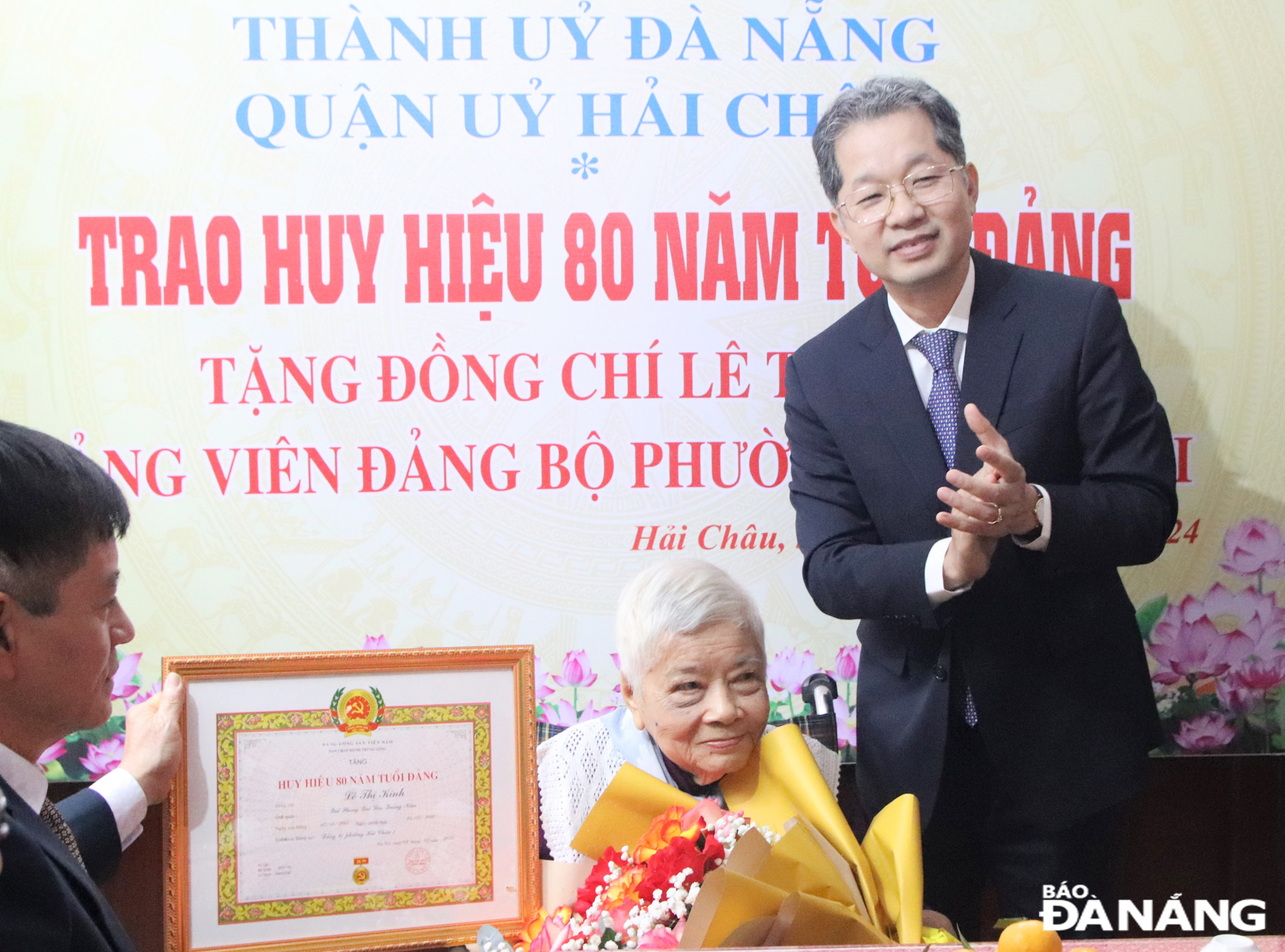 Bí thư Thành ủy Nguyễn Văn Quảng trao Huy hiệu 80 tuổi Đảng và tặng hoa chúc mừng đảng viên Lê Thị Kinh. Ảnh: TRỌNG HUY