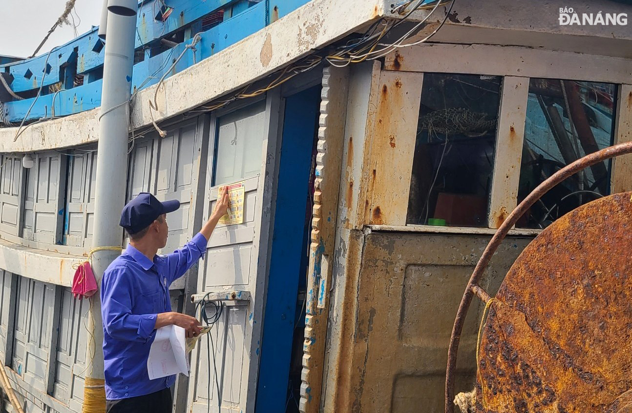 Nhân viên Ban Quản lý âu thuyền và cảng cá Thọ Quang dán các tờ hướng dẫn các biện pháp bảo đảm an toàn phòng, chống cháy, nổ tại ca bin các tàu cá. Ảnh: HOÀNG HIỆP