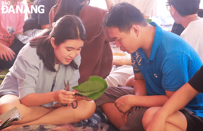 A Blisskidz Club member (first, from left) instructs a child to wrap 'banh chung' 