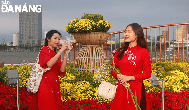 Taking advantage of the sunny weather, Ms. Tran Minh Chau (first, right) and her sister dress up in 'ao dai' and do makeup to take a series of Tet photos. Ms. Chau said that this is the ideal time to take photos when the flower street has just been completed because it is very beautiful and the number of people is not too crowded.