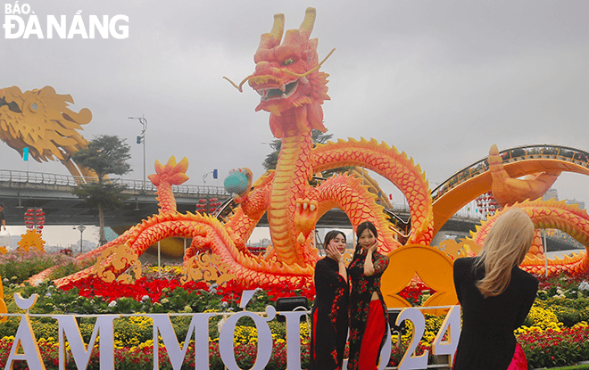 Not only the Bach Dang flower street, many people and tourists also gather in a public park on the eastern side of the Dragon Bridge. In the photo: Japanese tourists wearing 'ao dai' to take photos with the Dragon mascot at the park on the east bank of Dragon Bridge in Son Tra District.