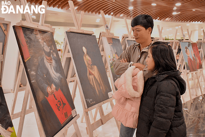 Before Lunar New Year's Eve, Mr. Do Ngoc Son, a resident of Hoa Quy Ward, Ngu Hanh Son District, and his daughter, visit a painting exhibition at APEC Sculpture Garden. 