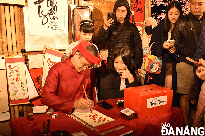 People gather in large numbers at a space for calligraphy writing on Bach Dang Flower Street with the hope of achieving their wishes in the coming year.