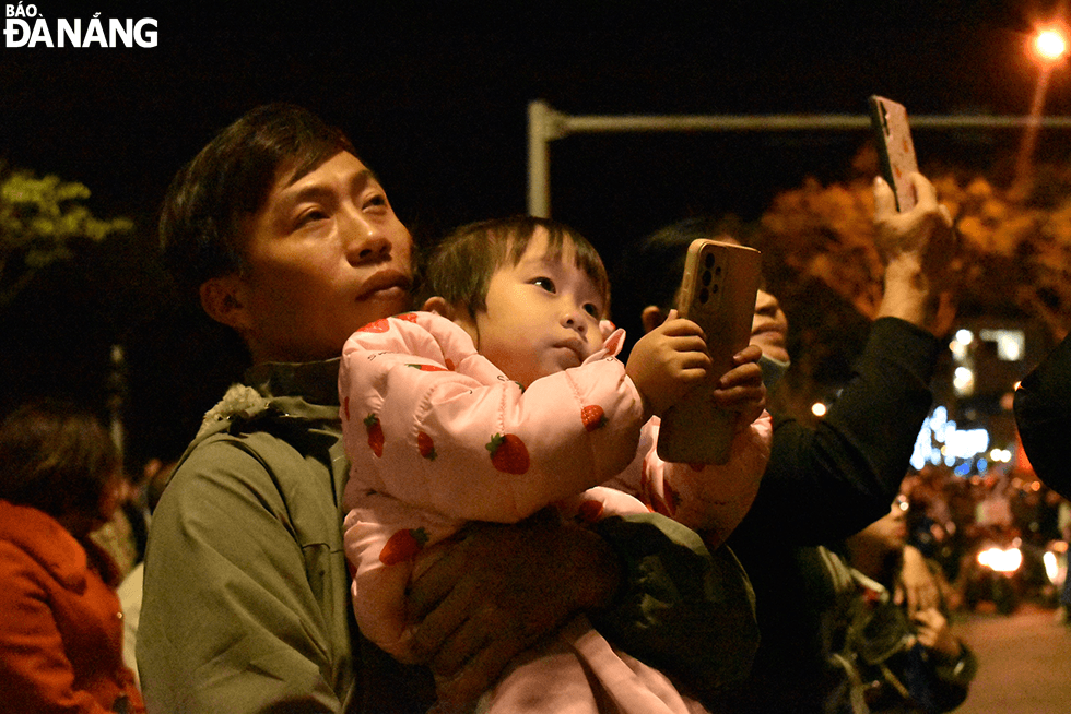   Children are held in the arms of their parents to watch the fireworks display. Photo: THU DUYEN