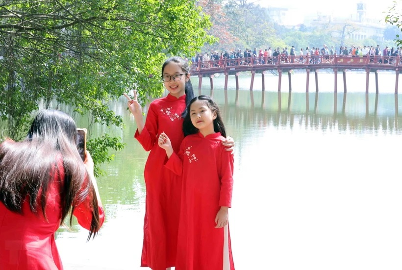 Người dân ghi lại hình ảnh đẹp bên cầu Thê Húc, quận Hoàn Kiếm, trong mùng 2 Tết. (Ảnh: TTXVN)