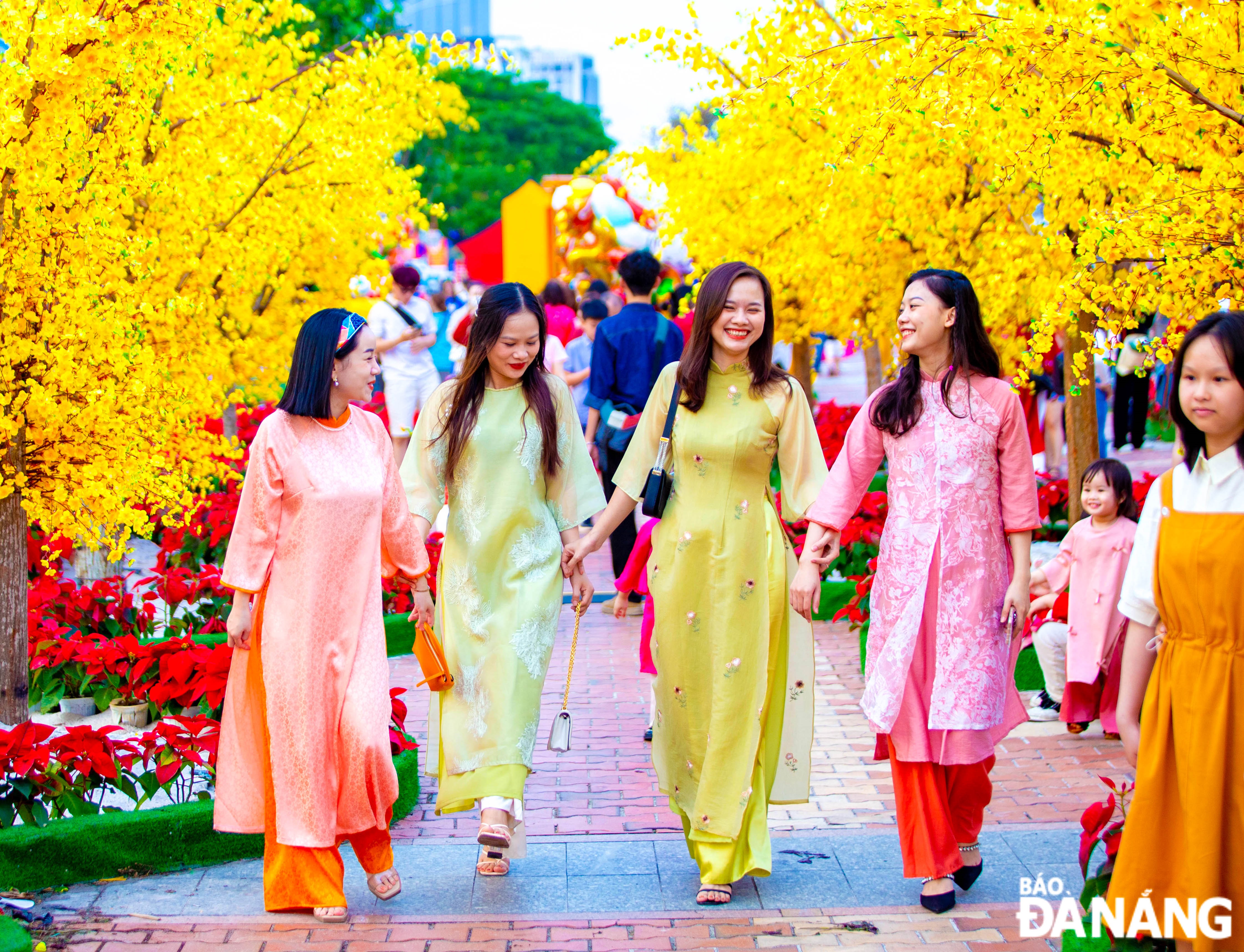 Girls dressed up in graceful 'ao dai' going for a stroll along the Bach Dang flower street.