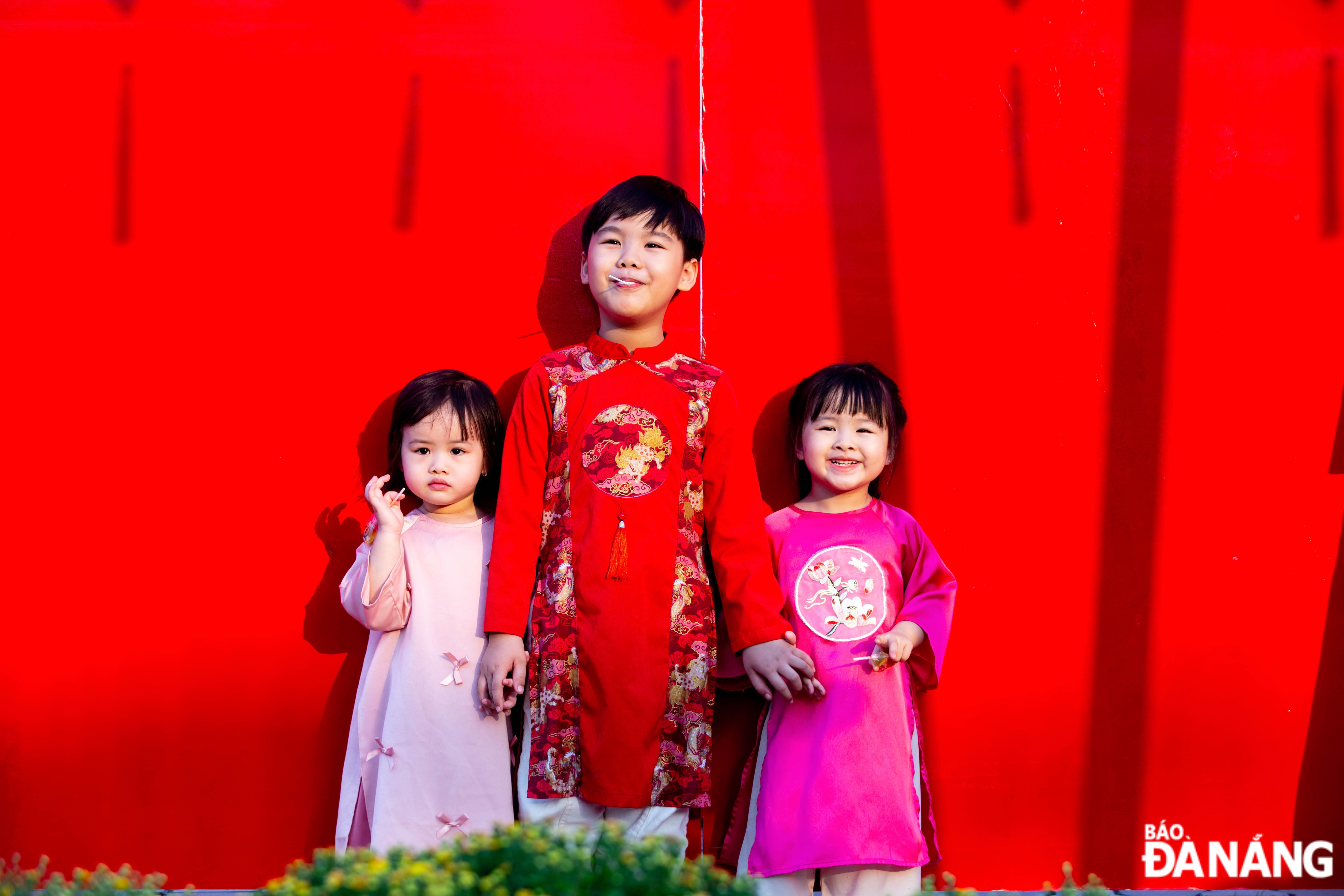 Children dress up in 'ao dai' to pose for Tet photos at the Bach Dang flower street.