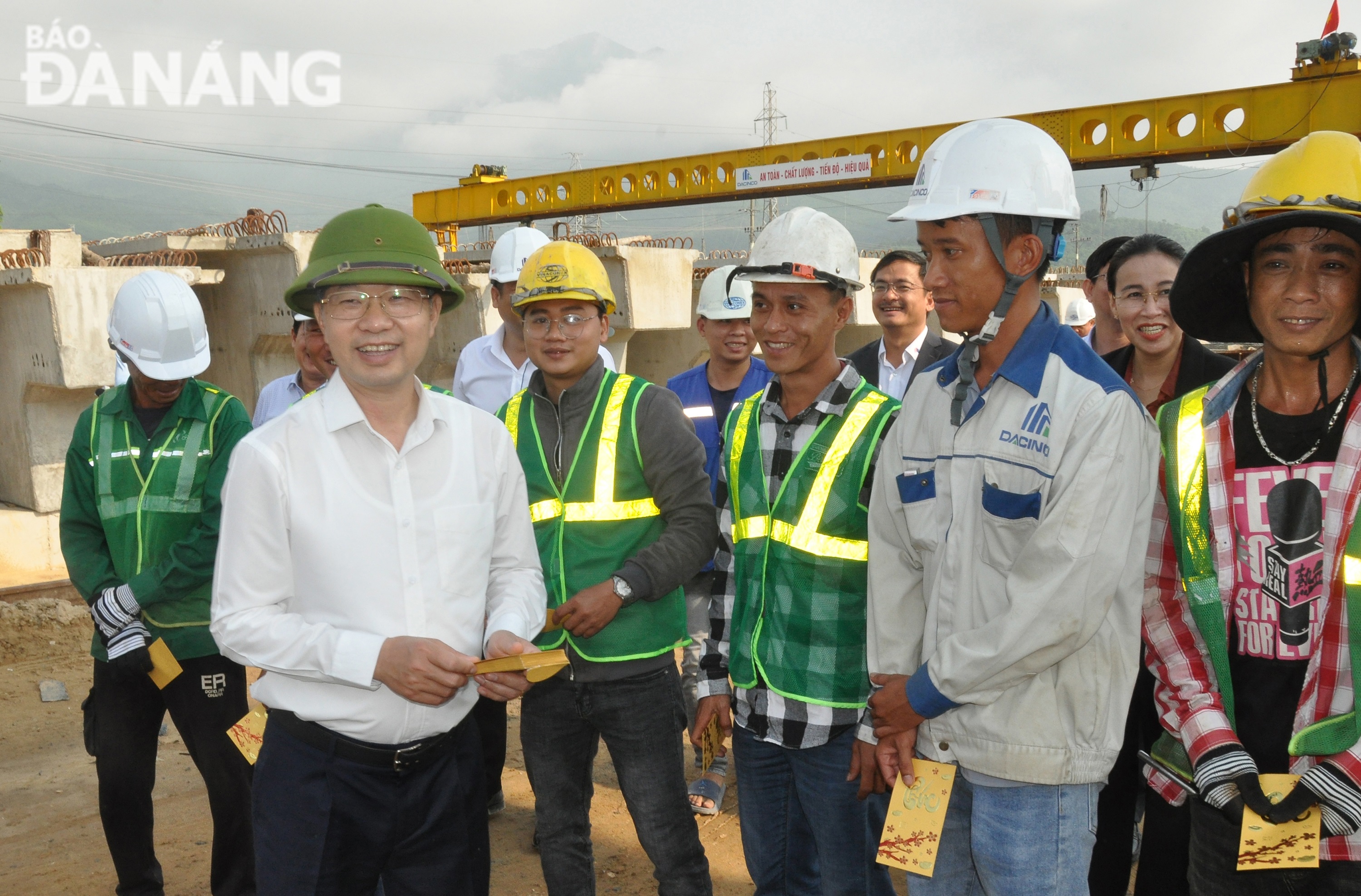 Secretary Nguyen Van Quang (white shirt) giving lucky money to construction workers. Photo: THANH LAN