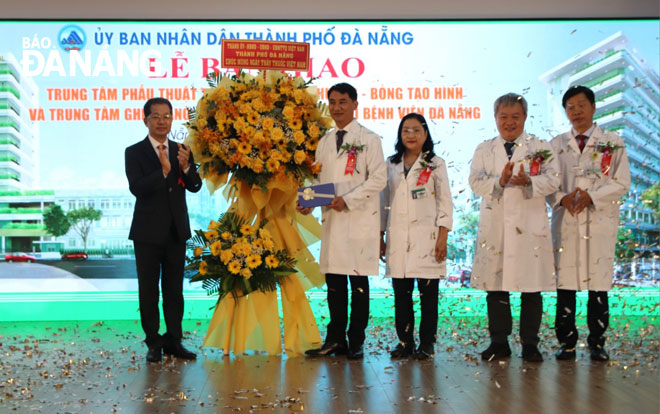 Da Nang Party Secretary Nguyen Van Quang (left) present flowers to congratulate the Da Nang General Hospital team upon receiving the two specialised medical projects. Photo: PHAN CHUNG