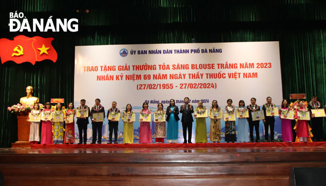 The city leaders present Certificates of Merit and flowers to 20 'Shining White Blouse' Award honourees. Photo: PHAN CHUNG