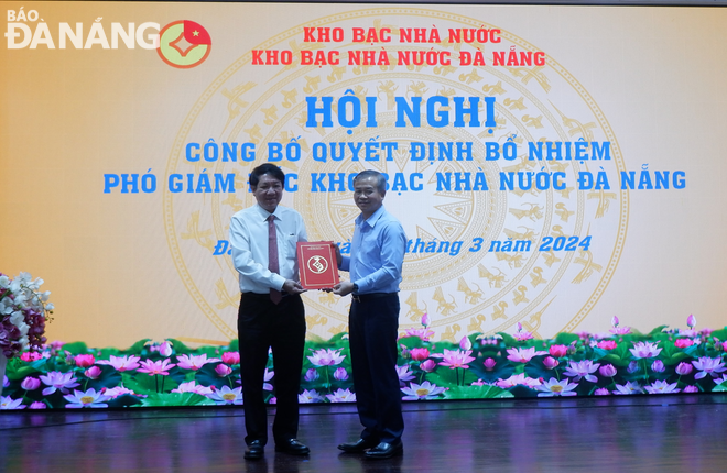 Thừa ủy quyền của Tổng Giám đốc Kho bạc Nhà nước Việt Nam, Phó Tổng Giám đốc Kho bạc Nhà nước Việt Nam Nguyễn Quang Vinh (phải) trao quyết định bổ nhiệm ông Lê Thanh Tùng, Giám đốc Kho bạc Nhà nước Sơn Trà giữ chức vụ Phó giám đốc Kho bạc Nhà nước Đà Nẵng