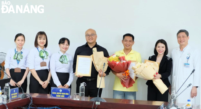 Social workers (white shirts, left) and leaders of the Da Nang Oncology Hospital (first, right) giving flowers to representatives of benefactors who have accompanied the hospital over the past year 