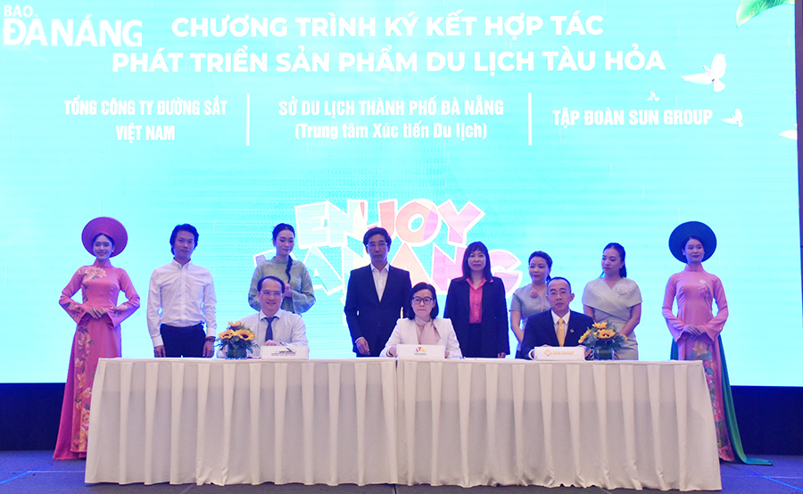 Vice Chairman of the Da Nang People's Committee Tran Chi Cuong (4th, from right, standing row) witnessing the signing ceremony of cooperation agreements  between representatives of the local tourism industry and transport service providers. Photo: THU HA