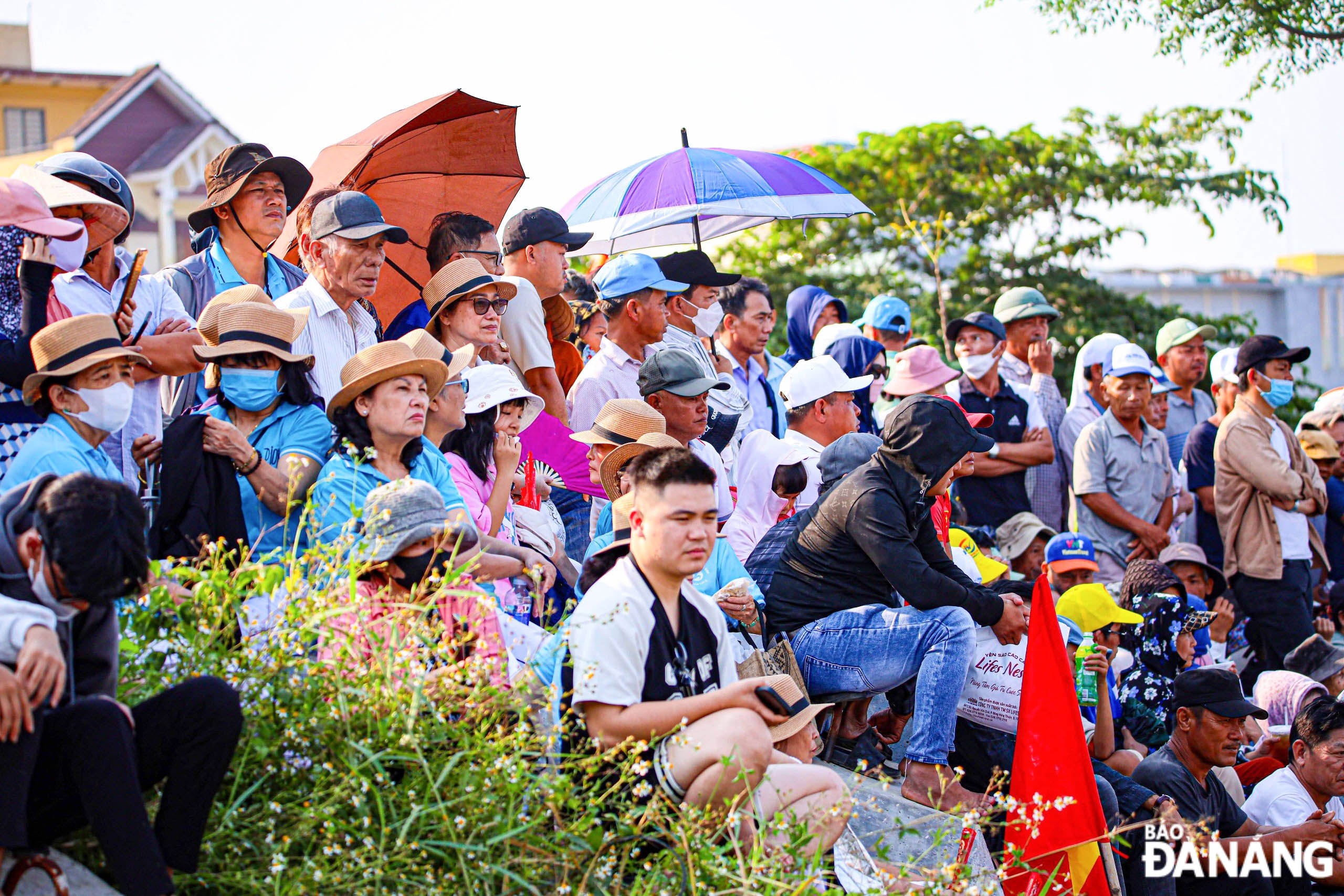 Spectators gathering along the riverbank to cheer for the racing boats.