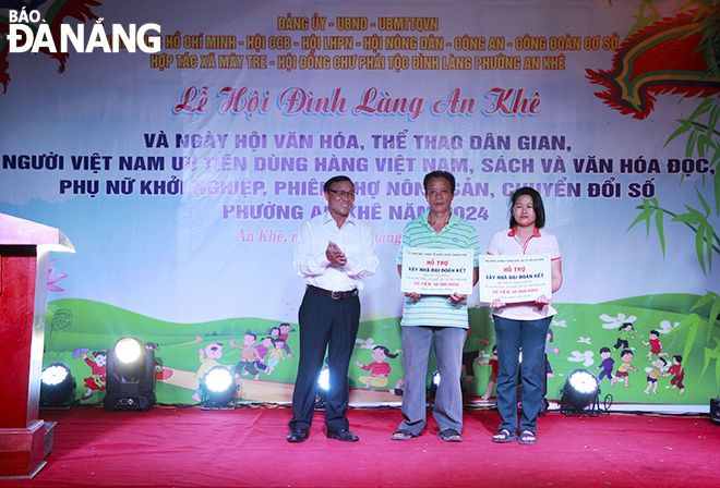 A representative of the Viet Nam Fatherland Front Committee of An Khe Ward giving funds to build and repair houses to 2 poor social policy households with VND50 million each. Photo: X.D