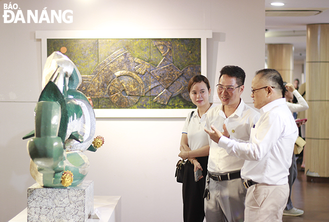 Artist Than Trong Dung (first, right) introducing some artworks in the exhibition to viewers.