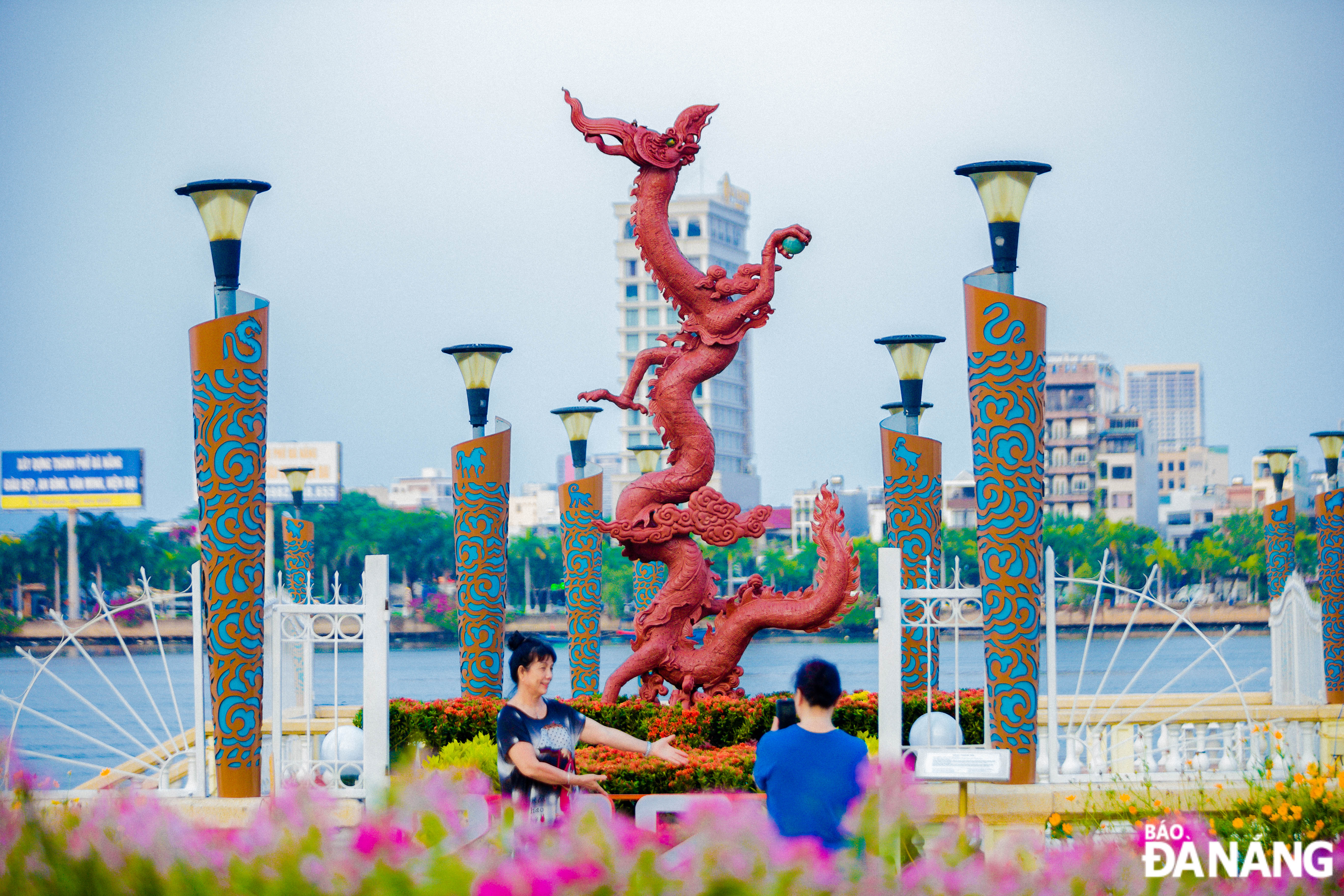 People take photos to preserve moments with the Ly Dynasty-style dragon statue at the flower street on Bach Dang Street