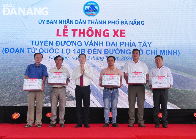 Da Nang Party Committee Secretary Nguyen Van Quang (3rd, left) presenting gifts to representatives of households which have been relocated to hand over the road construction site. Photo: THANH LAN